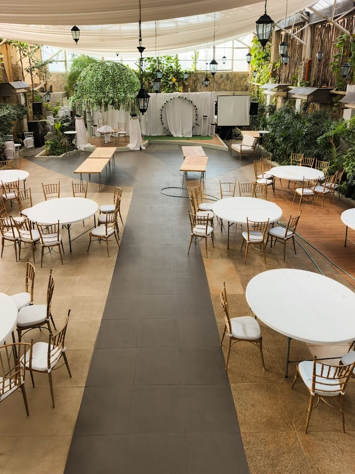 Spacious event venue with tables and chairs arranged for a gathering, featuring ample natural light.